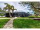 Beautiful, screened lanai with ample lounging space surrounded by a landscaped yard with palm trees at 75 Spyglass Aly, Placida, FL 33946