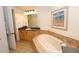 Bright bathroom featuring a soaking tub and sink with dark countertops, and artwork at 99 Vivante Blvd # 404, Punta Gorda, FL 33950