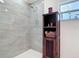 Tiled shower and brown shelving unit in this renovated bathroom at 1027 Campbell St, Port Charlotte, FL 33953
