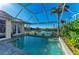 Screened pool with a view of the water, lush landscaping, brick pavers, and a hot tub at 1368 Grebe Dr, Punta Gorda, FL 33950