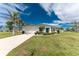 Charming single-story home featuring a well-manicured lawn, a bright blue front door and a spacious two car garage at 16271 Branco Dr, Punta Gorda, FL 33955