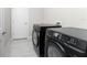 Laundry room featuring side-by-side dark-colored washer and dryer units and a white door at 16271 Branco Dr, Punta Gorda, FL 33955