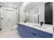 Bright bathroom featuring double vanity with blue cabinets and a modern glass shower at 1631 Casey Key Dr, Punta Gorda, FL 33950