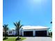 Front elevation of a modern-style home with a metal roof, well-maintained lawn, and contemporary garage doors at 1631 Casey Key Dr, Punta Gorda, FL 33950