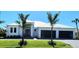 Beautiful new construction home with a metal roof, three-car garage, and lush landscaping with palm trees at 1631 Casey Key Dr, Punta Gorda, FL 33950
