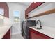 Modern laundry room with red cabinets, stainless steel appliances, and ample counter space at 1631 Casey Key Dr, Punta Gorda, FL 33950