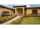 Inviting front entrance with double doors, manicured landscaping, and a charming fountain feature at 17327 Wintergarden Ave, Port Charlotte, FL 33948