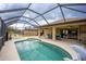 Large screened outdoor pool area with ceiling fans, dining table, and lush landscaping at 17327 Wintergarden Ave, Port Charlotte, FL 33948