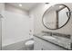 Bathroom featuring a tiled bathtub, toilet, single sink vanity and round mirror at 17954 Saddle Rd, Punta Gorda, FL 33982