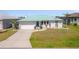 Charming single-story home with a green metal roof, manicured lawn, and paved driveway at 18662 Arapahoe Cir, Port Charlotte, FL 33948