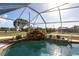 Tranquil in-ground pool with a custom rock waterfall feature and surrounding landscaping, enclosed within a screened lanai at 20339 Gentry Ave, Port Charlotte, FL 33952