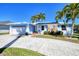 Inviting single-story home with a blue exterior, stone accents, mature palm trees, and an attached garage at 2180 Via Esplanade, Punta Gorda, FL 33950