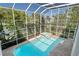 Aerial view of a screened-in pool and hot tub surrounded by lush landscaping at 250 George Rd, Port Charlotte, FL 33952
