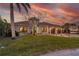 Stunning single-story home with manicured lawn and circular entryway, set against a vibrant sunset sky at 257 Lido Dr, Punta Gorda, FL 33950