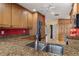 Spacious kitchen featuring granite countertops, wooden cabinets, stainless steel sink and a red accent wall at 258 Venezia Ct, Punta Gorda, FL 33950