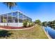 View of a beautiful screened in pool with lush landscaping next to a canal at 3024 Caribbean Dr, Punta Gorda, FL 33950