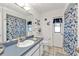 Bright bathroom with a white tile floor, blue floral shower curtain, and blue vanity at 321 Pessoa St, Punta Gorda, FL 33983