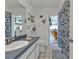 Bright bathroom with a white tile floor, blue floral shower curtain, and blue vanity at 321 Pessoa St, Punta Gorda, FL 33983