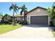 Inviting single-story home showcasing a manicured lawn, lovely palm trees, and a brick-paved driveway leading to the garage at 413 Valletta Ct, Punta Gorda, FL 33950