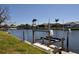 Scenic waterfront featuring lush green grass and a boat lift at 413 Valletta Ct, Punta Gorda, FL 33950