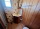 Compact bathroom featuring bright floral wallpaper, a corner sink, and wood-paneled accents at 6830 Pleasant Ct, North Port, FL 34287
