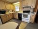 Functional kitchen featuring wooden cabinets, standard appliances, window view, and vintage wallpaper at 6830 Pleasant Ct, North Port, FL 34287