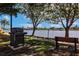 Community outdoor grill and bench seat near the water with a walking path and neighborhood homes beyond at 93 Vivante Blvd # 9323, Punta Gorda, FL 33950