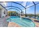 Beautiful screened pool with a small waterfall feature and an overview of the backyard landscaping at 13056 N Marsh Dr, Port Charlotte, FL 33953