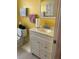 Bright yellow bathroom with white vanity, cabinet storage, toilet, and light tile flooring at 137 Revere Nw St, Port Charlotte, FL 33952