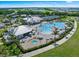 Aerial view of a resort-style pool with lounge seating, a hot tub, and lush tropical landscaping in gated community at 14049 Black Beauty Dr # 721, Punta Gorda, FL 33955