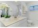 Bright bathroom with white marble vanity, a large mirror, white toilet and modern fixtures at 149 Sportsman Rd, Rotonda West, FL 33947