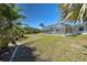 Lush backyard featuring a screened-in pool surrounded by mature palm trees, creating a serene and private outdoor space at 165 Cummins Ne Ave, Port Charlotte, FL 33952