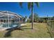 A beautiful pool with a screened-in lanai surrounded by palms and lush greenery in the backyard at 165 Cummins Ne Ave, Port Charlotte, FL 33952