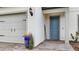 Close-up of a blue front door with a brick walkway and a two-car garage to the side at 2486 Buckthorn Loop, North Port, FL 34289