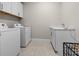 Clean laundry room equipped with modern washer and dryer, storage cabinets, and a sink at 2486 Buckthorn Loop, North Port, FL 34289