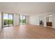 Bright living room featuring wood floors, large windows and balcony access with scenic green tree views at 25188 Marion Ave # D303, Punta Gorda, FL 33950