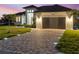Stunning home exterior with brick paver driveway, garage, and manicured lawn at twilight at 260 Long Meadow Ln, Rotonda West, FL 33947