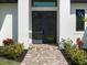 Detailed view of front entrance with double doors, decorative sidelight, and a brick pathway at 260 Long Meadow Ln, Rotonda West, FL 33947