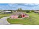 Well-manicured home featuring a circular driveway, lush landscaping, and a striking red front door, creating a grand entrance at 26389 Villa Maria Dr, Punta Gorda, FL 33983