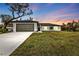 Charming single-story home with a lush green lawn, a two-car garage, and beautiful dusk skies at 267 Camrose St, Port Charlotte, FL 33954