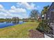 Scenic backyard view featuring a serene lake, lush green grass, and tropical palm trees at 2676 Wax Myrtle Ct, Port Charlotte, FL 33953