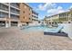 Community pool area with brick pavers, lounge chairs, and building exterior view at 3322 Purple Martin Dr # 127, Punta Gorda, FL 33950