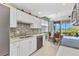 Bright kitchen features white cabinets, mosaic backsplash, stainless steel appliances, and access to screened patio at 3393 Grand Vista Ct # 101, Port Charlotte, FL 33953