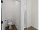 Half bathroom features wood-look tile flooring, white walls, toilet, and doorway to the tiled standing shower at 12156 Wellington Ave, Port Charlotte, FL 33981