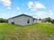 Exterior side view of gray house, AC unit, and large backyard at 12156 Wellington Ave, Port Charlotte, FL 33981