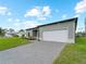 A modern single-Gathering home featuring a gray brick driveway, manicured lawn and well-maintained landscaping at 12156 Wellington Ave, Port Charlotte, FL 33981