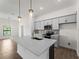 Modern kitchen boasts stainless steel appliances, a large island, and stylish pendant lighting fixtures at 12156 Wellington Ave, Port Charlotte, FL 33981