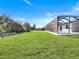 View of the backyard with a screened-in enclosure and sprawling lawn at 14319 Allensworth Ave, Port Charlotte, FL 33981