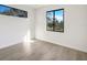 Bright bedroom showcasing wood-look tile flooring and natural light from two windows at 14319 Allensworth Ave, Port Charlotte, FL 33981