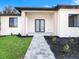 Stylish home entrance with a paved walkway, modern black double doors and black mulch accents at 14319 Allensworth Ave, Port Charlotte, FL 33981